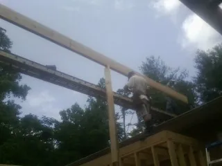 Carpenter setting a ridge beam over a new addition frame — Ice Dam Removal by Roofing Brothers in Houghton