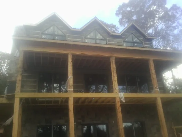 Dormers and porch framing on a large log home under construction — Roof Coating work by our crew in Houghton