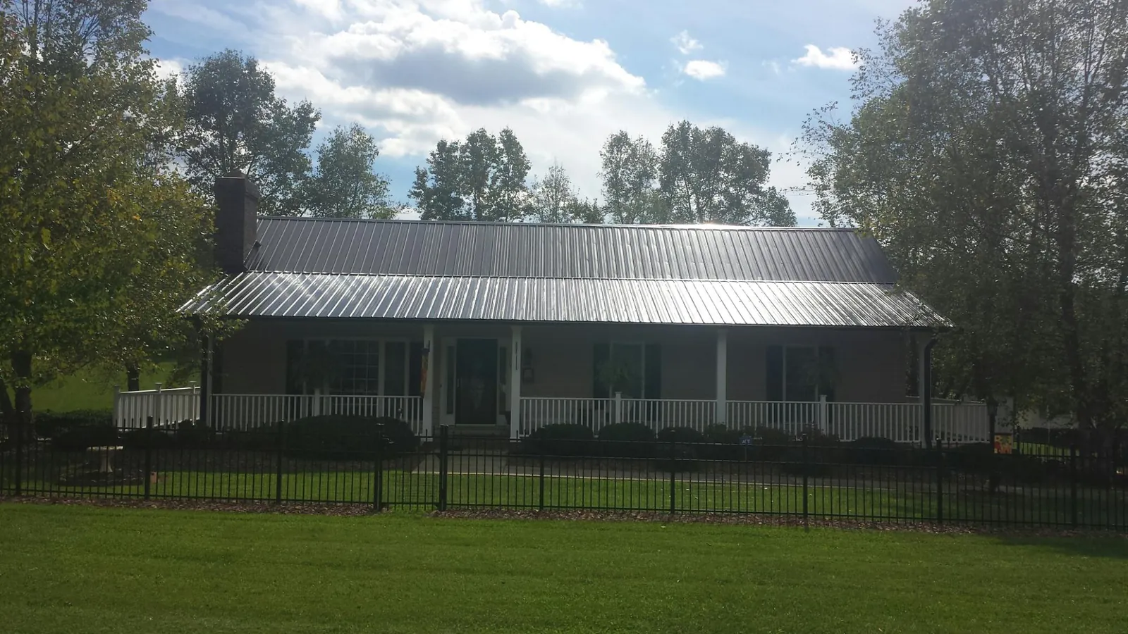 Gray metal roof on a brick ranch with a full width front porch — Gutter Guard Installation work by our crew in Houghton
