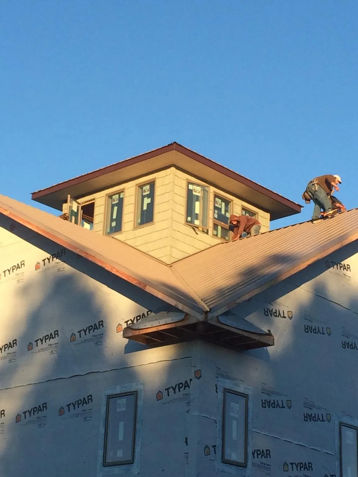 Roofers working around a rooftop cupola on a new metal roof at sunset — Roof Waterproofing in Houghton by Roofing Brothers